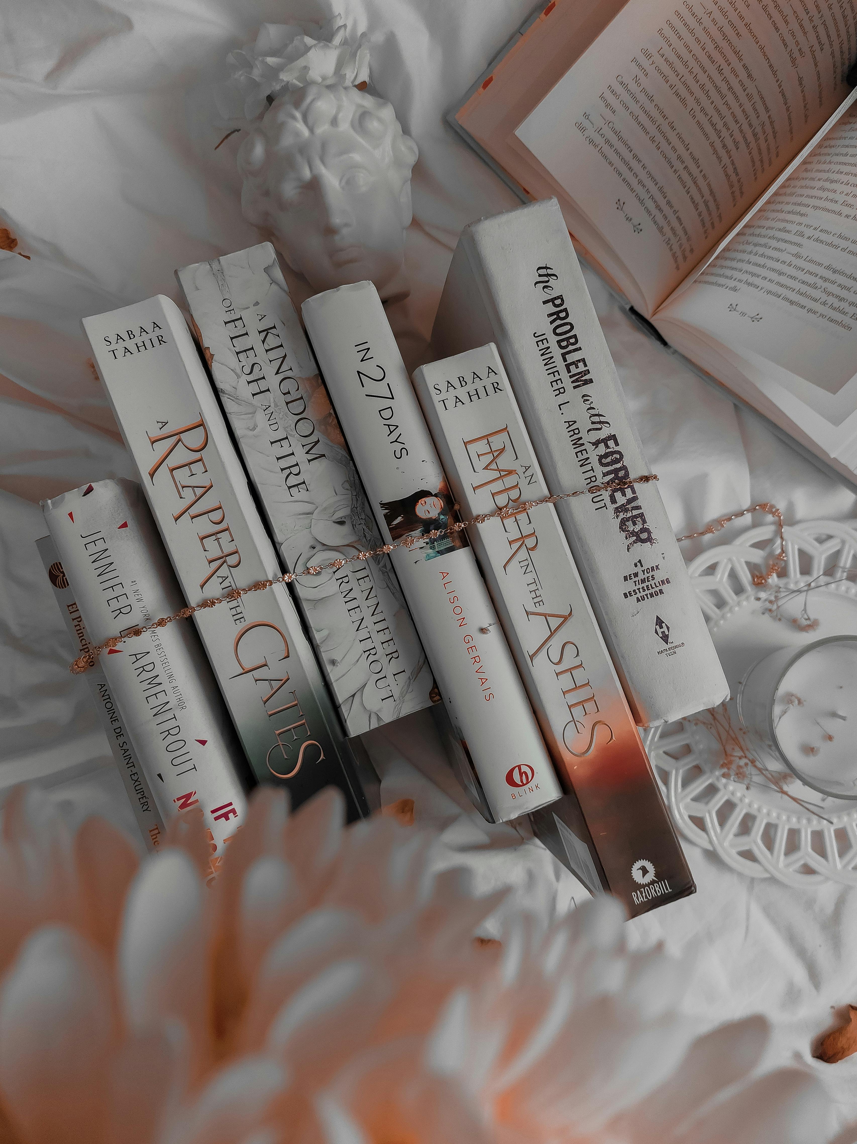 Aesthetic flatlay of six white books with red flowers, representing personalised book recommendations from The Book Muse.